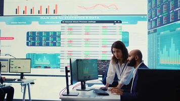 Teammates examining statistics and infographics on computer in control room, joining forces to gather insight for business development. Analysts discussing legal changes. Camera B. video