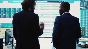 General director discussing with an investor to increase funding for a project, presenting performance metrics and annual data on a big screen. Business associates share strategies. Camera A. video