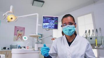 paciente pov olhando às dentista Perguntando para dental raio X mostrando dentes imagem. estomatologia especialista vestindo protetora mascarar, trabalhando dentro moderno estomatológico clínica, explicando radiografia do dente video