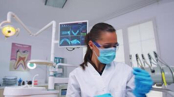 Dentist preparing anesthesia before tooth surgery, holding syringe with serum, pov patient. Doctor and nurse working in modern orthodontic office wearing protection mask and gloves video