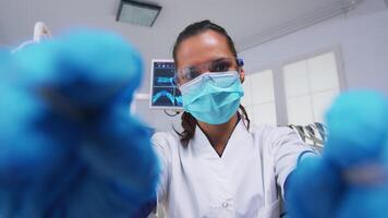 POV of patient in a dental clinic sitting on surgery chair while professional dentist working with gloves during examination in modern clinic using sterilized instruments video