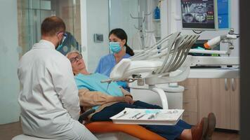 Dentistry doctor doing hygienic cleaning of teeth using sterile dental tools. Patient lying with open mouth in stomatological office, stomatologist performing examination in modern clinic. video