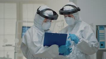 Close up of dentistry doctors talking wearing hazmat suit with face shield, mask, and coverall. Caucasian dentist team discussing dental operation and consultation for teeth protection video