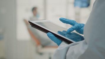 Close up of hand using dental x ray on modern tablet at oral clinic cabinet. Stomatology assistant holding device with radiography and scan technology examining teeth model for patient video