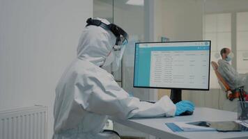 Dental assistant working on computer at dentistry clinic for teethcare appointment and consultation. Nurse sitting at desk while professional stomatologist examining patient in background video