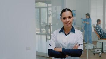 retrato do caucasiano estomatologista dentro uniforme sorridente e olhando às Câmera dentro dental escritório espaço. mulher com odontologia perícia e dentista profissão em pé às oral Cuidado clínica video