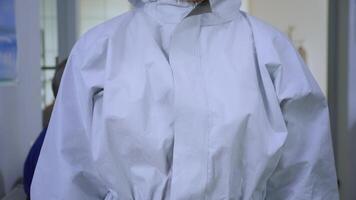 Close up of exhausted nurse in dental office looking on camera wearing ppe suit without face shield sitting on chair in waiting room clinic. Concept of new normal dentist visit in coronavirus outbreak video