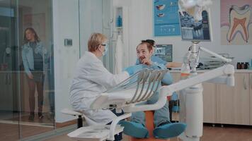 dentaire expert Faire examen à traiter patient avec carie dans dentisterie armoire. professionnel dentiste consultant homme avec oral se soucier problèmes, en utilisant stomatologie instruments pour inspection. video