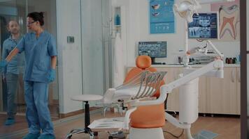 Patient arriving at dental checkup visit in stomatology cabinet, getting ready to do teeth examination with dentistry nurse. Assistant consulting man, doing inspection for oral care. video