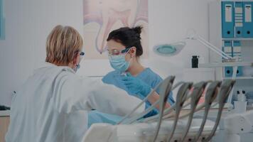 enfermero y estomatólogo examinando dientes de paciente, utilizando dental instrumentos a hacer perforar procedimiento para oral cuidado. odontología equipo haciendo dentadura inspección a tratar hombre con caries. video