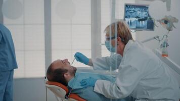 Stomatologist woman consulting patient after teeth procedure, analyzing denture with dental tools and instruments. Dentistry expert doing oral care examination in stomatological cabinet. video