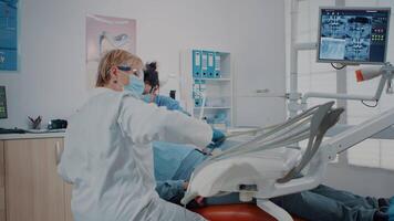 Woman dentist using instrument to do drill procedure, treating patient with toothache. Stomatologist examining denture with dental tools for oral care inspection. Dentistry inspection video