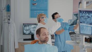 Sénior dentiste et infirmière en cours d'analyse X rayon analyse à trouver diagnostic, à la recherche à dentier radiographie résultats à traiter patient avec mal aux dents. dentaire expert et assistant Faire ral se soucier examen video