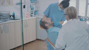 Stomatologist and nurse using dental tools to examine dentition work after surgery at oral care clinic. Dentistry team doing teeth consultation on patient to cure cavity problem. video