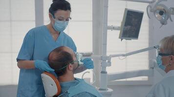 Dental Assistent mit Sauerstoff Maske zu tun Anästhesie auf geduldig Vor beginnend chirurgisch Verfahren beim Oral Pflege Klinik. Krankenschwester geben Betäubungsmittel zu Mann, durchführen stomatologisch Operation. video