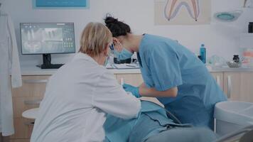 stomatologue et infirmière Faire extraction procédure sur patient avec mal aux dents. équipe de spécialistes en utilisant dentaire outils à effectuer chirurgie à stomatologique examen dans dentisterie bureau. video