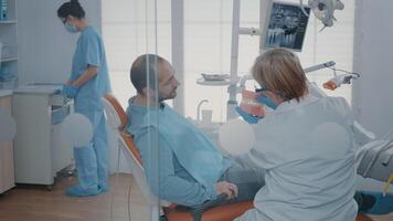 dentiste donnant hygiène leçon à patient à nettoyer les dents correctement avec brosse à dents et dentifrice dans stomatologie bureau. expert montrant oral se soucier routine sur artificiel mâchoire à prévenir carie. video