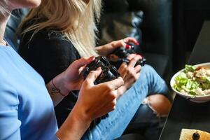 Two Women Sitting Together, Holding Game Controllers photo