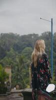 blonde woman with long hair standing with her back to the camera against jungle video