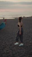 Girl running along a black beach against a backdrop of fishing boats at sunset video