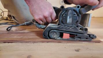 Carpenter hands hold a sanding machine. A woodworker carefully sands a wooden floor using a sanding machine. video