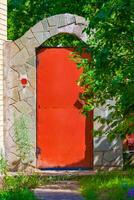 red metal door in the estate with an arch of lined stone tiles photo