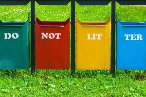 Four colors trash can in the park with inscription - do not litter photo