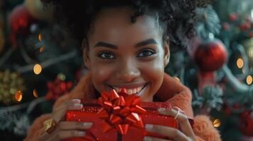 un mujer participación un Navidad regalo en frente de un Navidad árbol foto