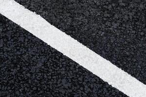 White diagonal marking line on the asphalt road as background, texture, abstract photo