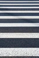 View of white markings pedestrian lines on a asphalt road as background, texture photo