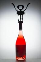 View of a corkscrew on a rose wine bottle on a white backlight background photo