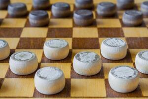 wooden checkerboard with checkers spaced on table photo