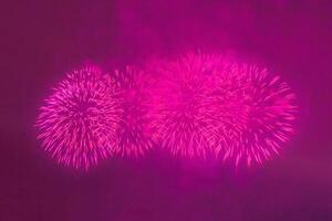 Purple festive fireworks on dark sky background photo