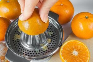 Preparing of mandarin juice, hands squeeze juice on a manual juicer photo