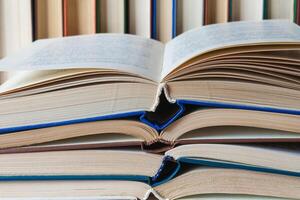 Stack of books with an open book on top, in the background the books stand in a row photo