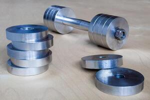 Steel dumbbell with pancakes on a wooden floor photo