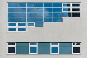 Modern facade of glass and concrete reflecting sky and clouds photo