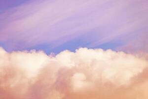 Orange fluffy clouds illuminated by the sunlight against a gently pink sky background photo