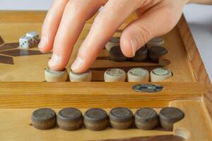 Wooden backgammon board with player hand, closeup photo