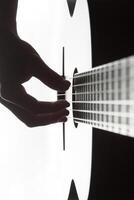 Man' s hand playing on classical guitar against a background of daylight photo