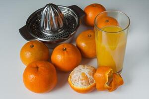 Glass of healthy fresh juice of mandarins and manual juicer on white background photo