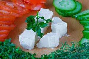 Closeup feta cheese with vegetables and herbs ingredients for salad photo