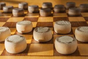 wooden checkerboard with checkers spaced on table photo