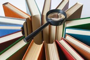 Books are arranged in a circle in the center on them lies a magnifying glass search concept photo