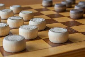 wooden checkerboard with checkers spaced on table photo