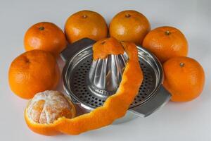 Manual metal juicer surrounded by mandarins on white background photo