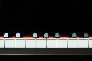 Piano keys front view on a black background, closeup, copy space photo