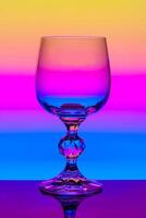 Crystal wine glass on a background of multi colored gradient photo