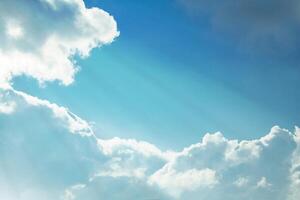 The rays of the sun illuminate the fluffy white clouds a background of bright azure sky photo