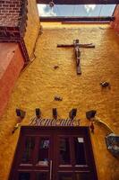 Playa del carmen Mexico 20 august 2022 Yellow Wall with a dark wooden door and a very large crucifix hanging behind it a symbol of Christian beliefs in South America photo